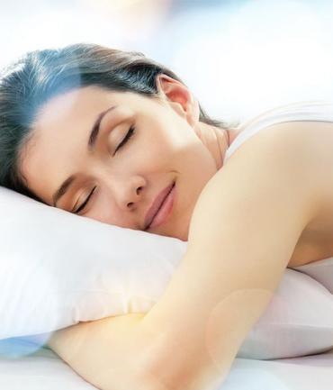 Femme détendue dormant paisiblement, illustrant un sommeil réparateur et une relaxation profonde, favorisant le bien-être global.