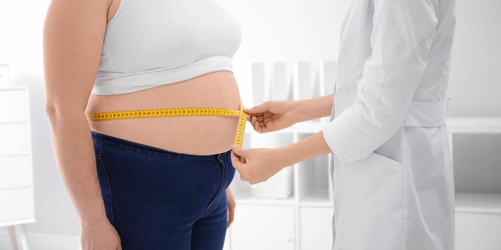 Mesure du tour de taille d’une femme en consultation, illustrant un accompagnement personnalisé pour la perte de poids et la santé globale.