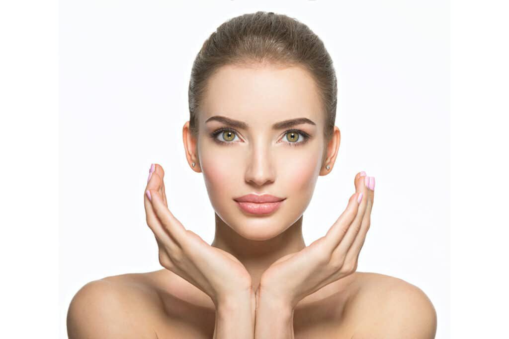 Femme au teint éclatant posant avec élégance, symbolisant les bienfaits des soins du visage pour une peau lumineuse et revitalisée.